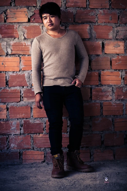 a young man leaning on a brick wall