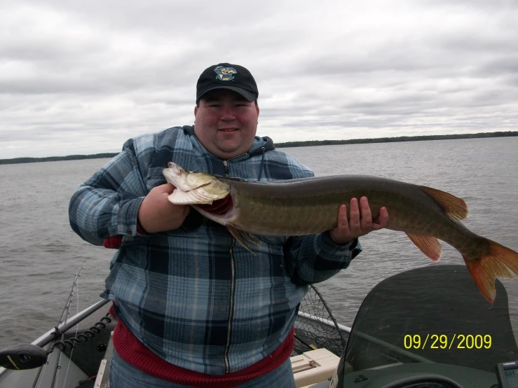 a man in plaid jacket holding a fish in water