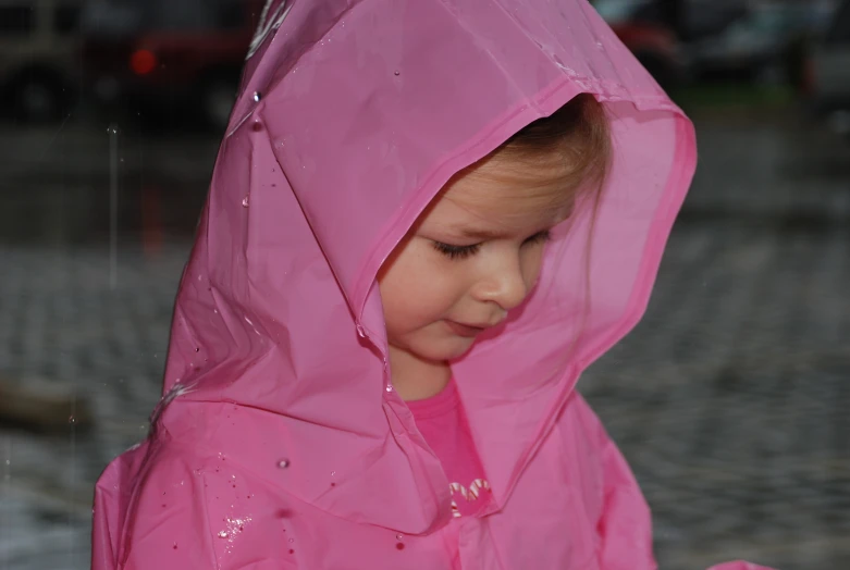 a little girl that is wearing pink and wearing a rain coat