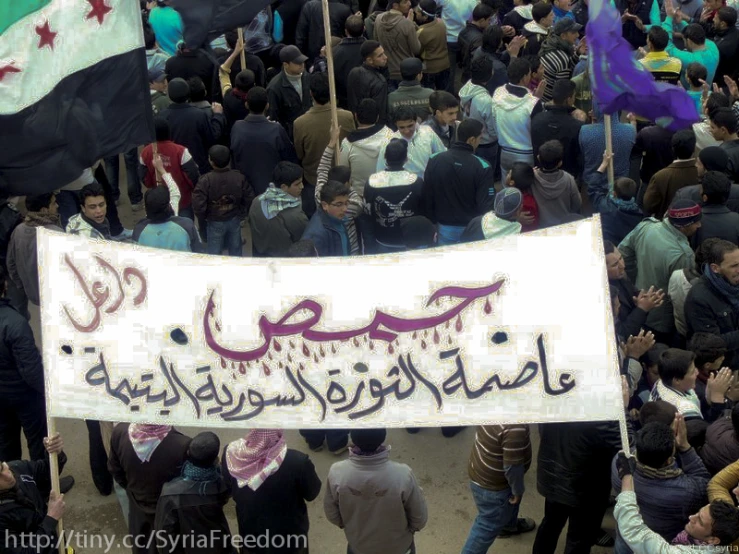 a large crowd holds up a banner that reads