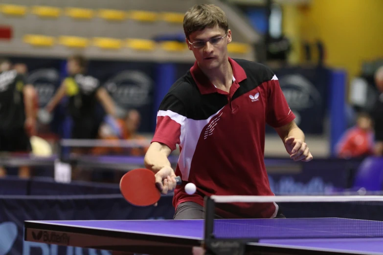 a male professional player is holding his ping pong racket