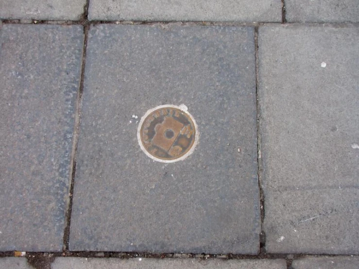 a manhole cover sitting in the cement on a sidewalk