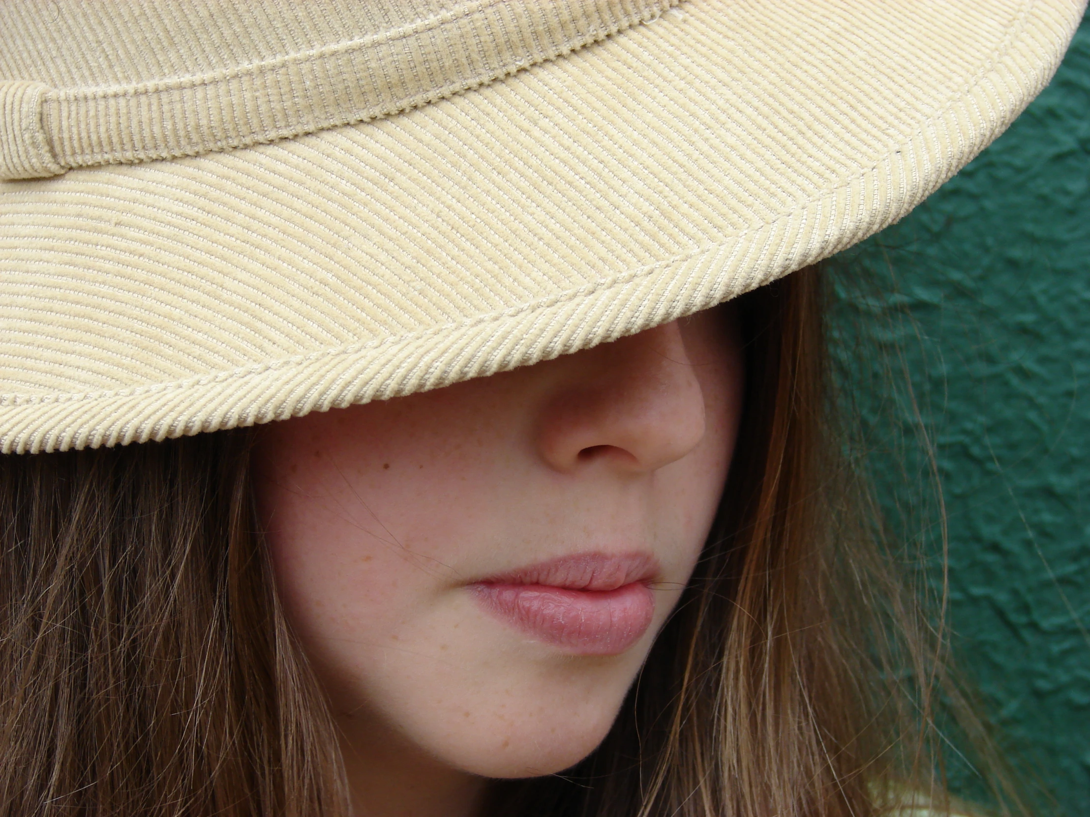 the young woman with a tan hat is close to her face