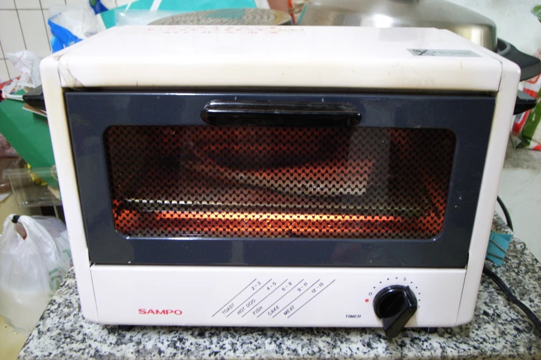 a toaster oven sits on a counter top with items in the background