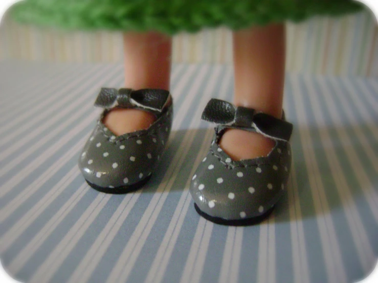 a toy baby girl's feet in polka dot shoes