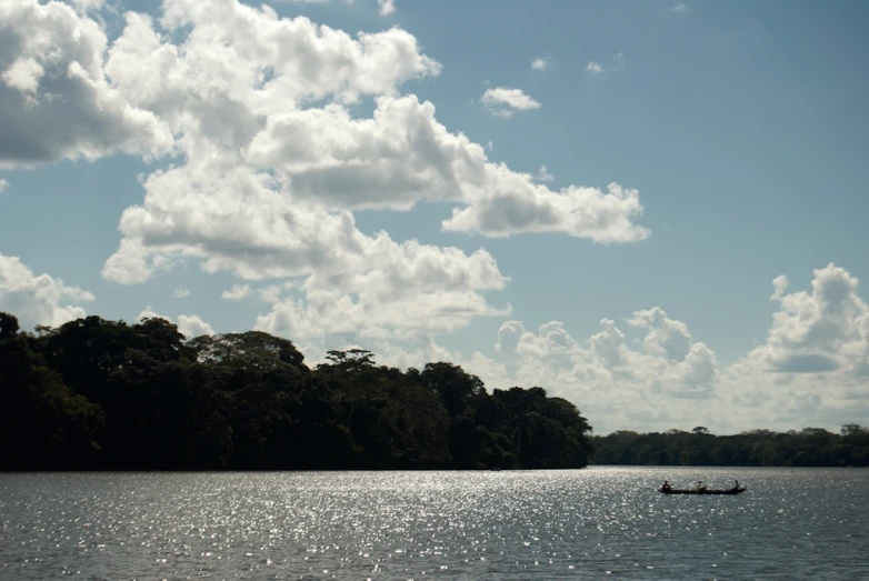 a man in a boat on a lake under a cloudy sky