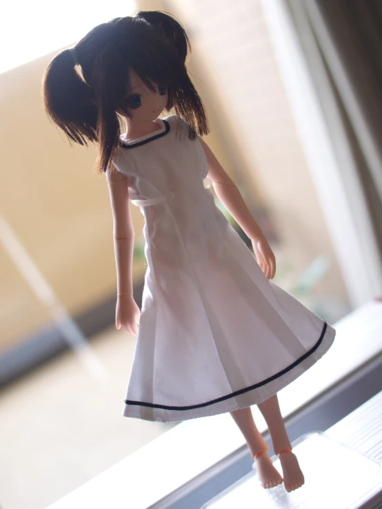 a doll wearing a white dress is standing on a window sill