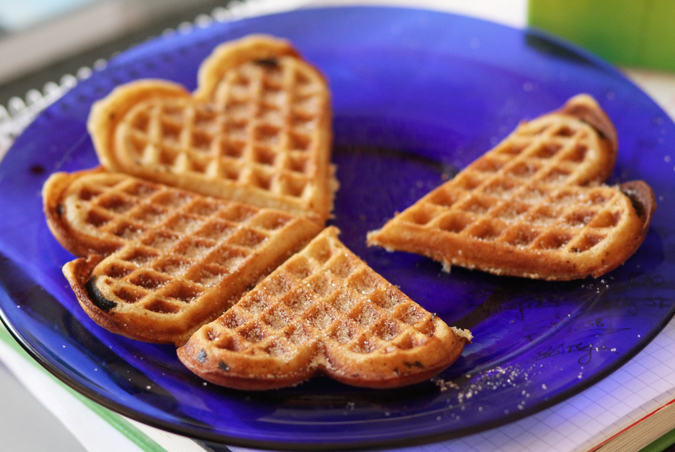 heart shaped waffles on a blue plate sitting on a desk