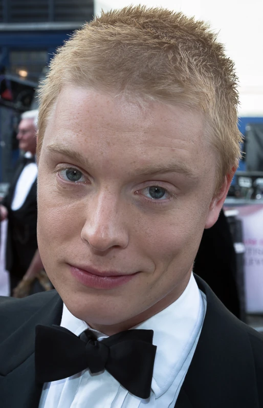 a young man with a suit and tie is looking into the camera