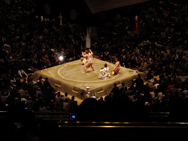 two sumo wrestlers on stage with a crowd looking on
