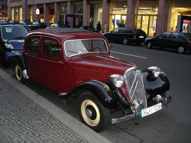 vintage car with classic emblem parked in front of a sidewalk