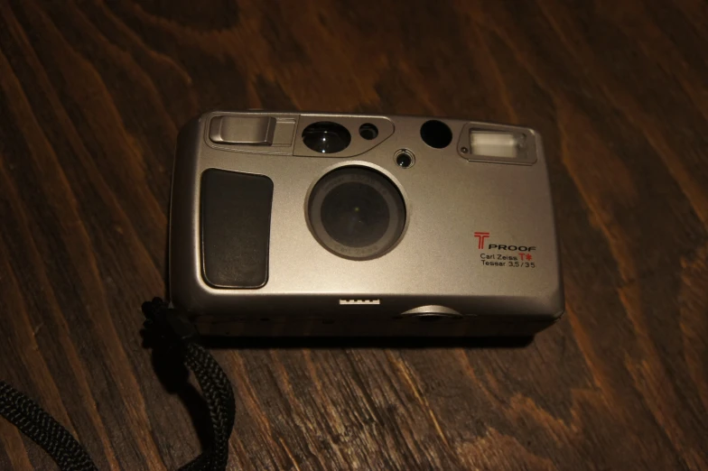 this silver compact camera is displayed with a cord