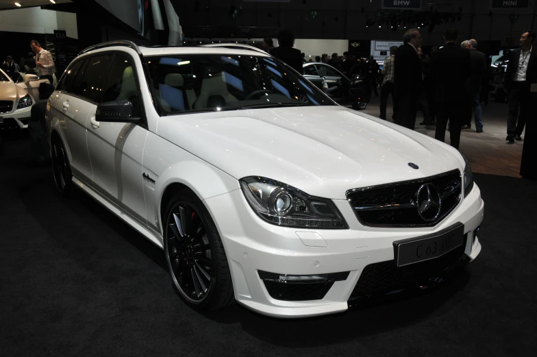 a white mercedes is parked on display at a car show