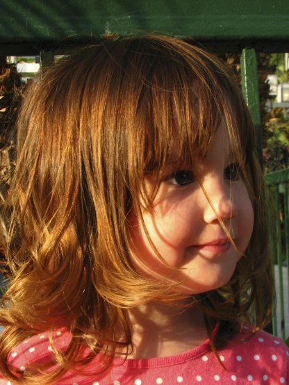 little girl standing with long wavy hair in yard