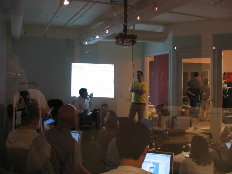 a group of people in a room with laptops