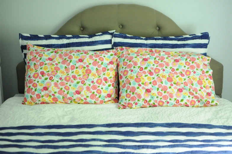 a colorfully designed bed has blue, white, and orange striped pillows