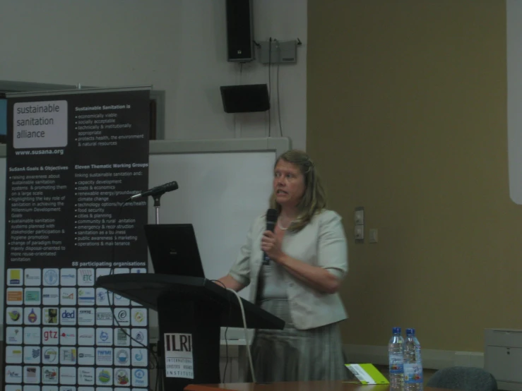 woman speaking at podium in front of large group