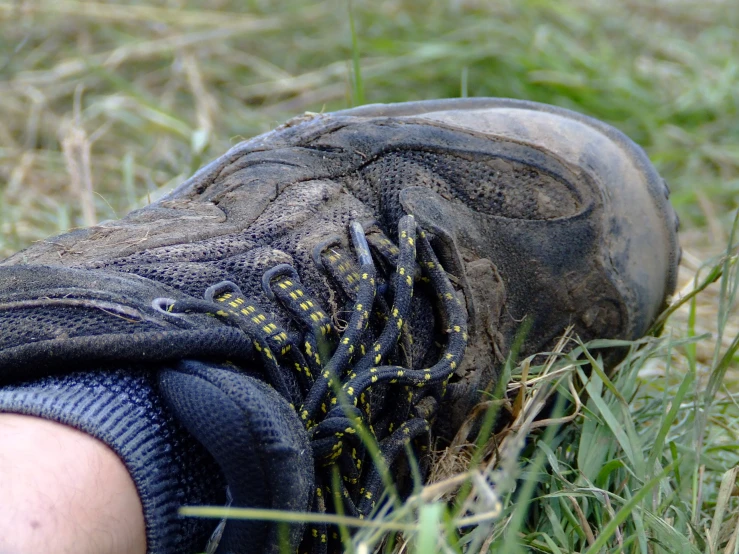 a persons foot standing in some grass and dirt