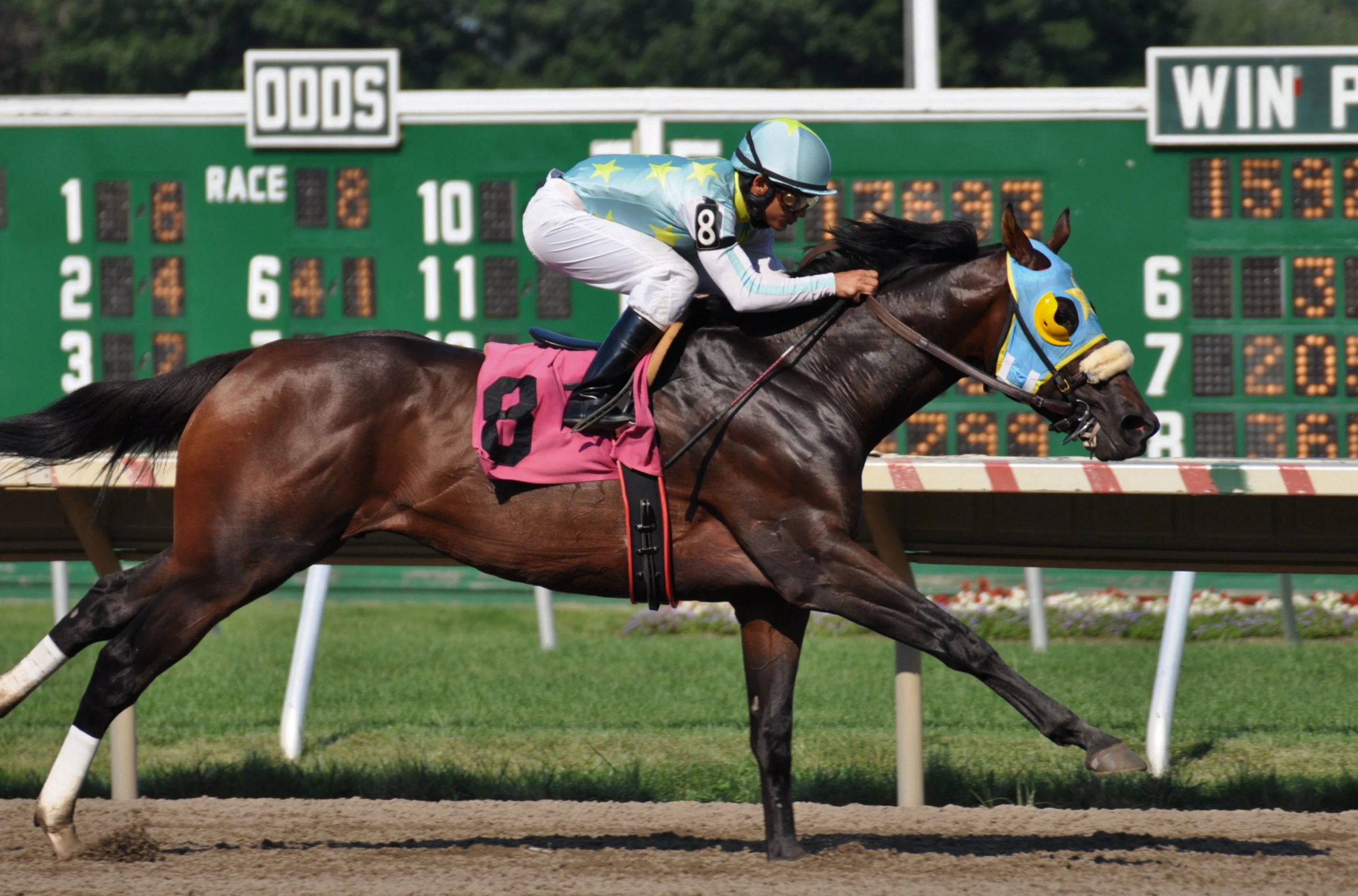 a man riding on the back of a brown horse down a race track