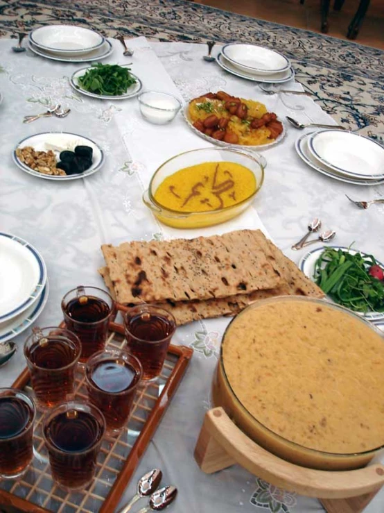 an array of dishes, wine glasses and a platter of food sit on a table