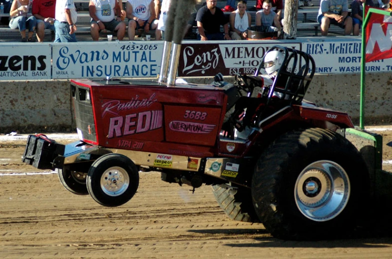 a man is racing a tractor in a dirt track