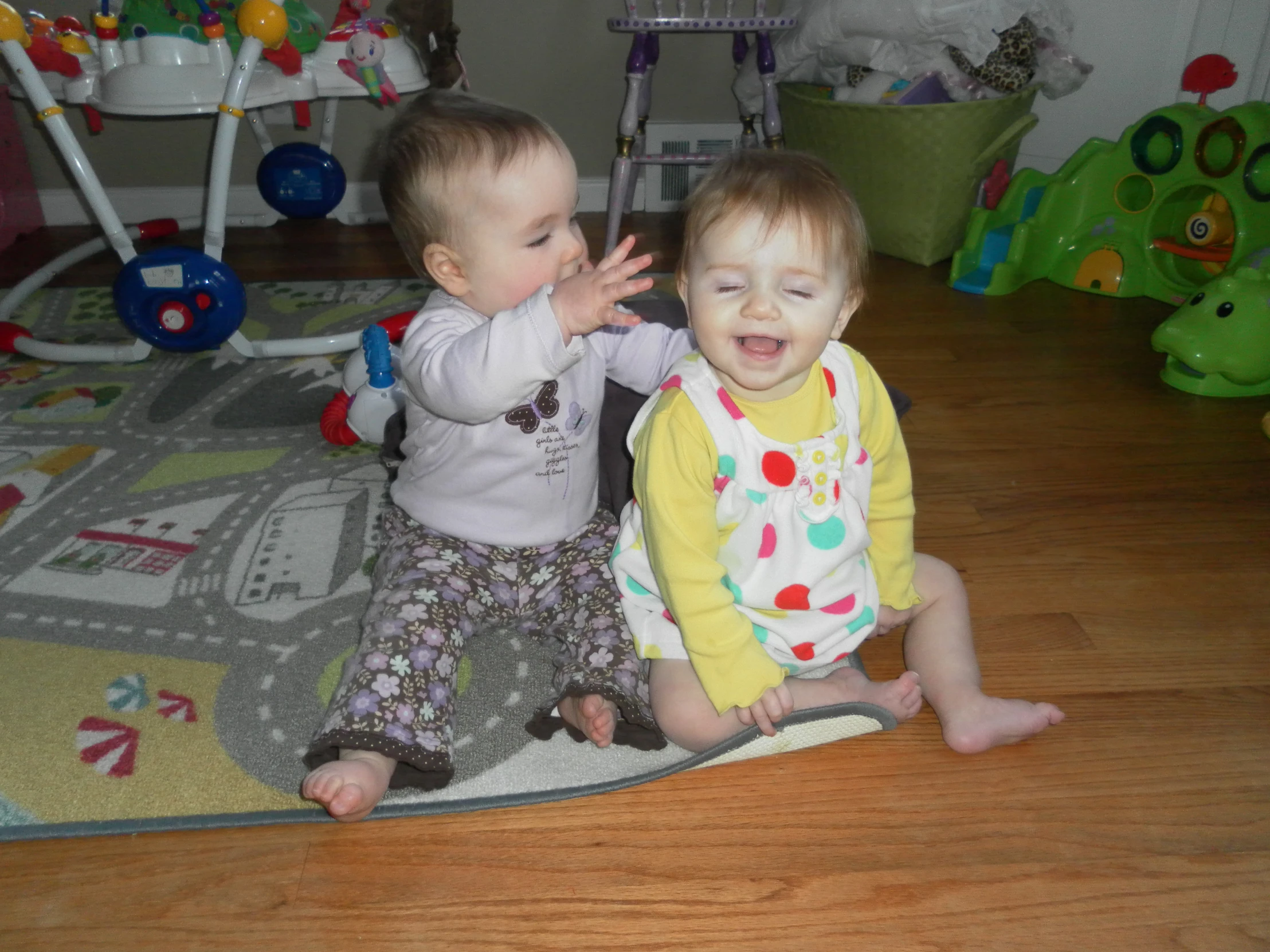 two toddlers play together in the living room