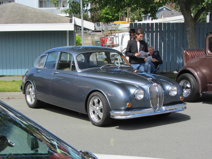 two guys sitting on the bonnets of a vintage car