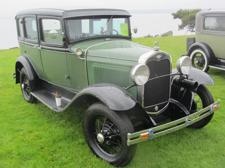 two cars sitting on the grass, one in green and the other silver