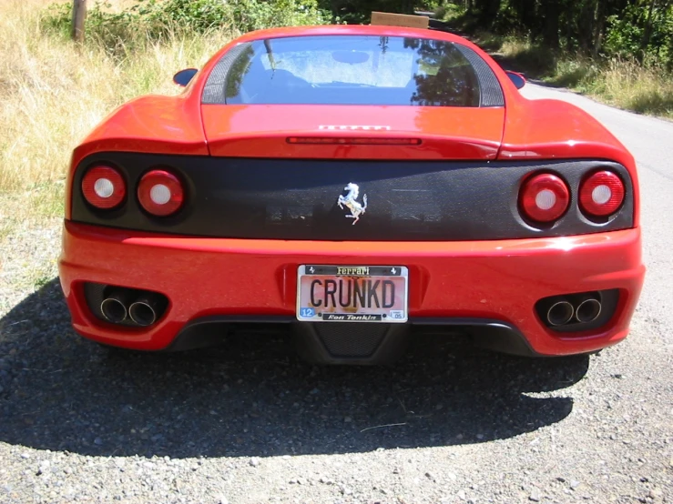 red sports car parked in gravel near trees