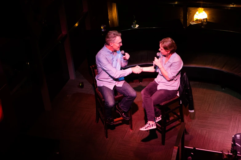 two people sitting on chairs in a dark room