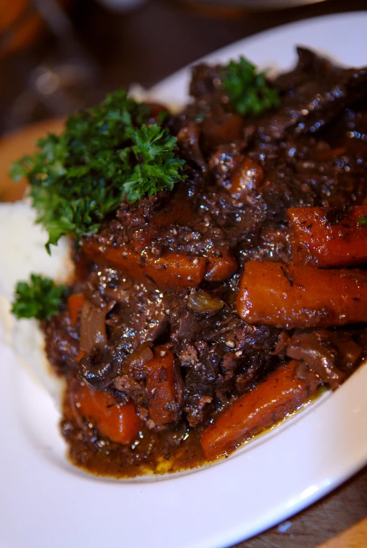 cooked meat with carrots, potatoes and gravy on a plate