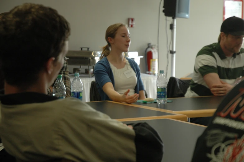 three people sitting at a table with cups and bottles on it