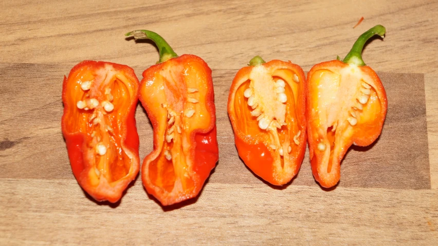 peppers are sitting on a  board with a wooden surface