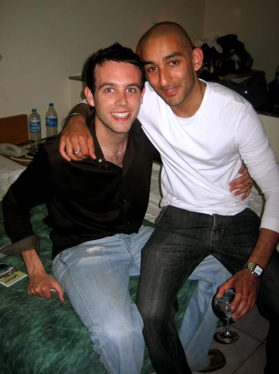 two young men pose together on a bed