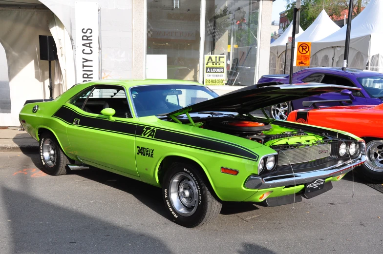 a green muscle muscle car parked next to another vintage american muscle