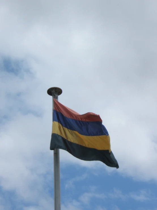 a close up of a multi colored flag on top of a pole