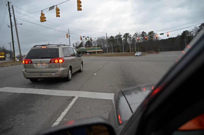 two cars stopped at an intersection in the rain