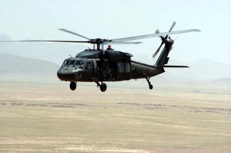 a large helicopter flying in the sky over a desert