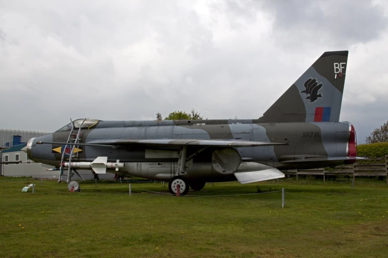 a gray fighter jet parked in a grassy area