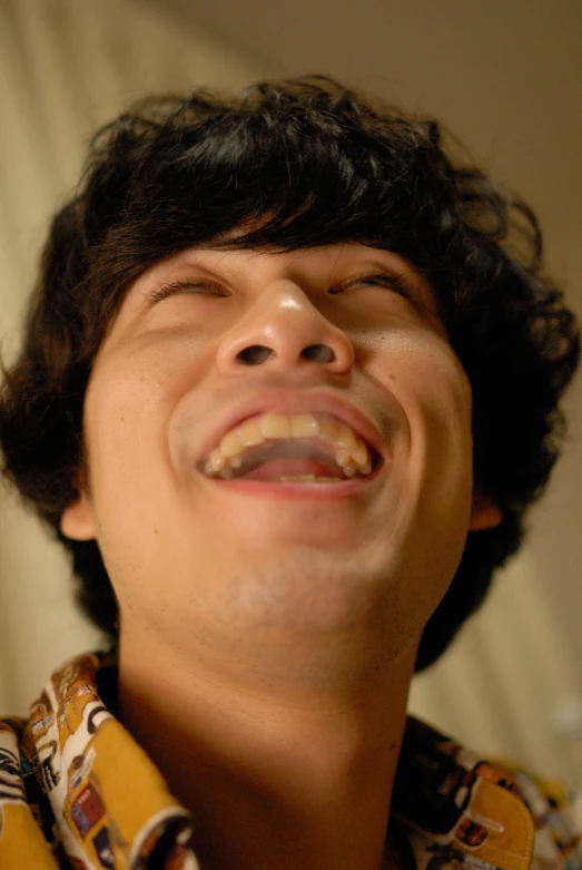 a close - up of a man with dark hair and a on - down shirt has his mouth open wide open