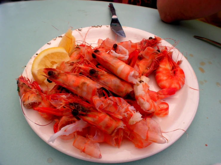 shrimp, lemon and black pepper are arranged on a plate