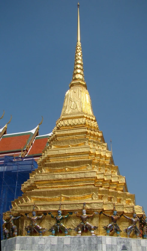 a gold statue is standing in front of a pagoda