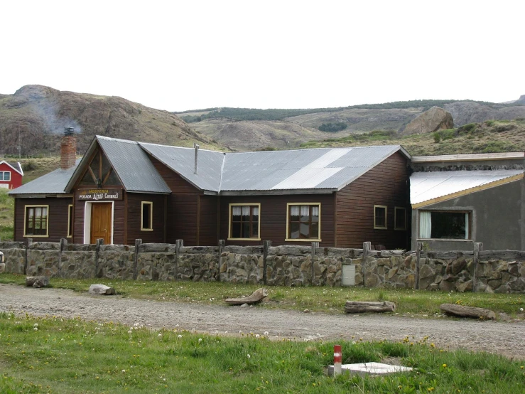 a house with large rocks behind it on a grass field