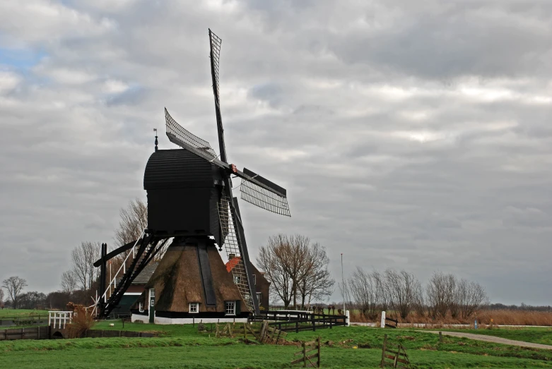 a windmill sitting next to a road with cars driving by