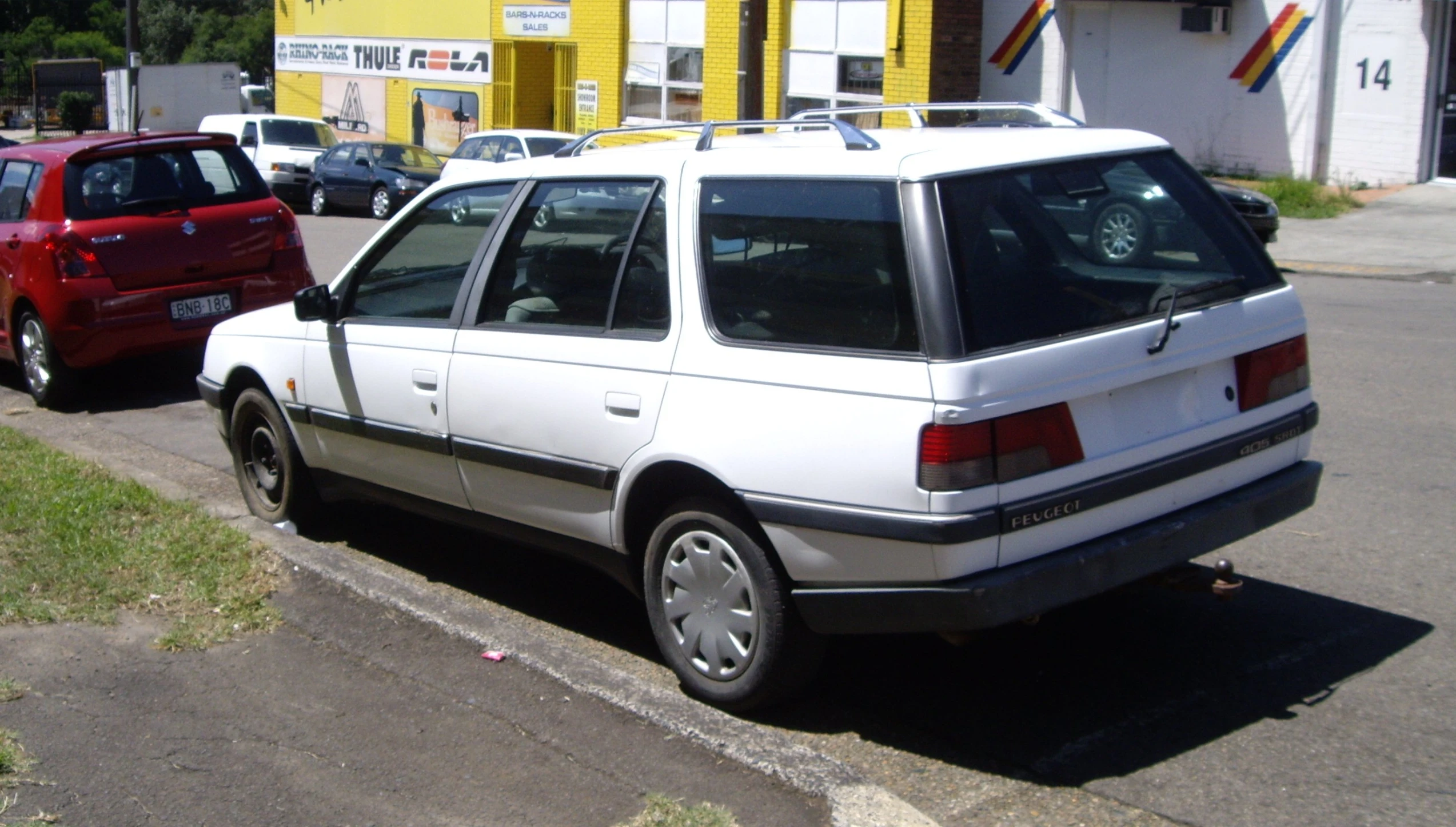 a white station wagon parked next to other cars on a street