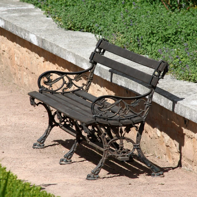 the old bench is in a courtyard near a wall