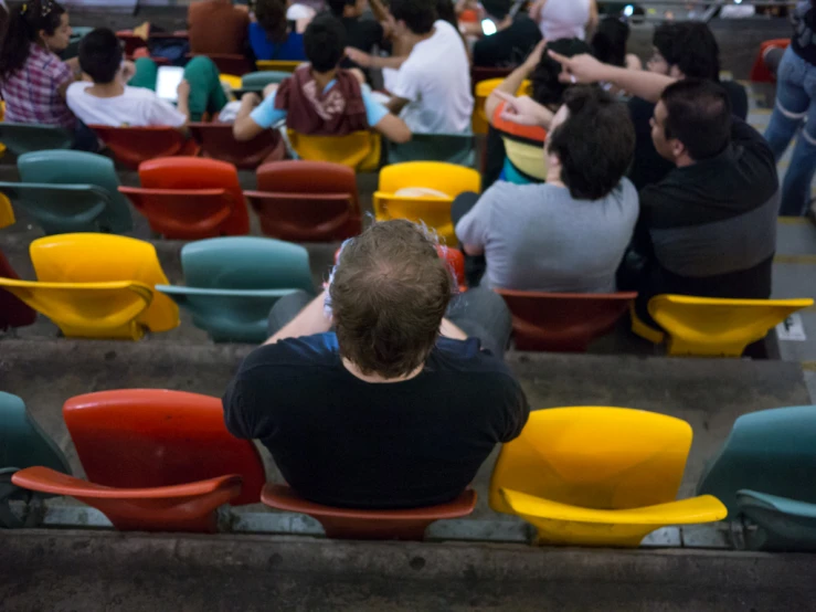 a crowd of people sitting in chairs and standing around