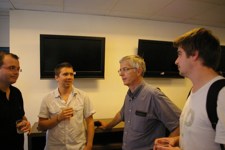 three men with glasses and one holding a drink