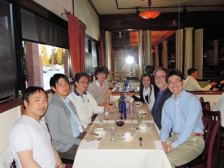 a group of people sitting at a dining room table posing for the camera