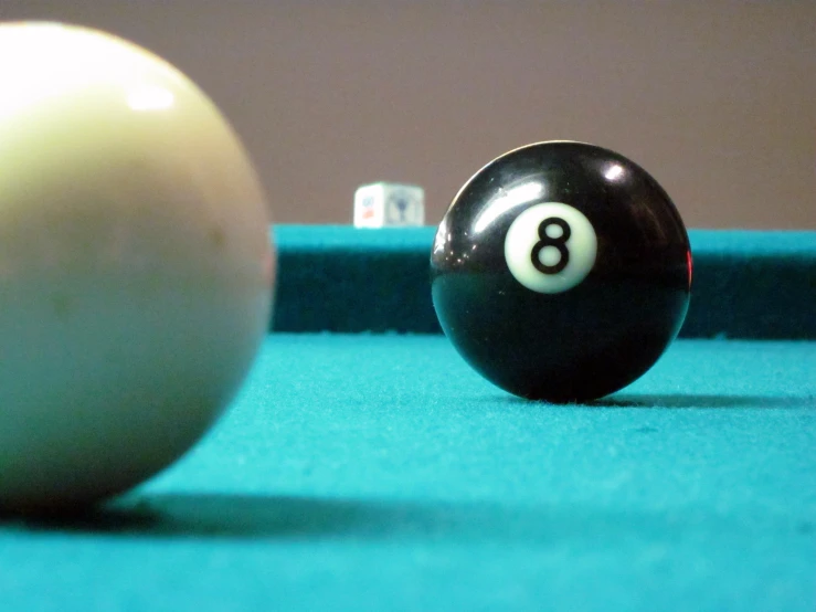 a pool ball on a green cloth with two white and black balls
